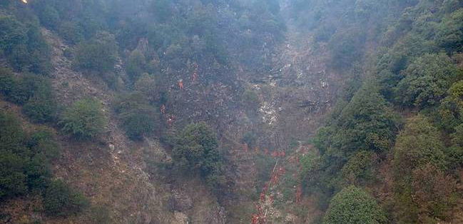 森林消防员在凉山火场近70度陡坡挺进 背20公斤的灭火装备爬山