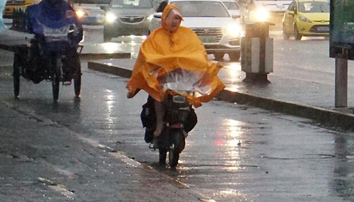 女子骑电动车雨伞盖头狂奔1公里 路人提醒危险却不予理会